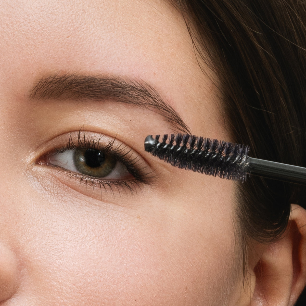 Application du Ricigel à la brosse sur les cils supérieurs d'une modèle aux yeux verts, soin des cils L'Atelier du Sourcil