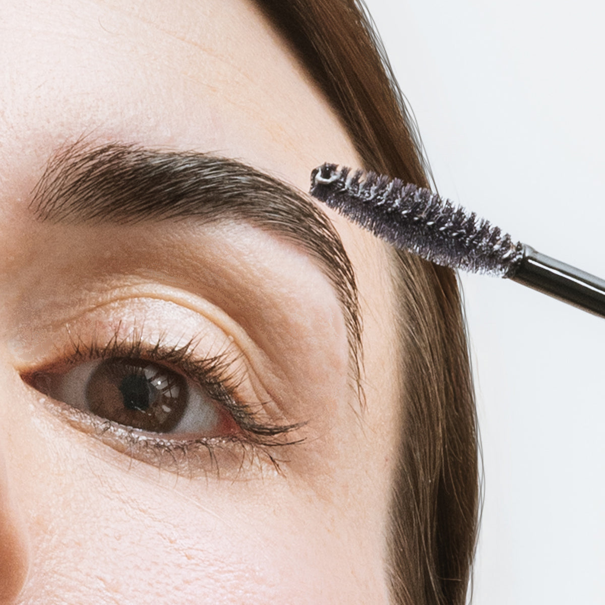 Application du Browshape transparent sur le sourcil brun d'une modèle aux yeux marron, gel fixateur L'Atelier du Sourcil